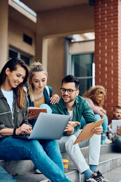 Happy college friends surfing the net on laptop at campus.
